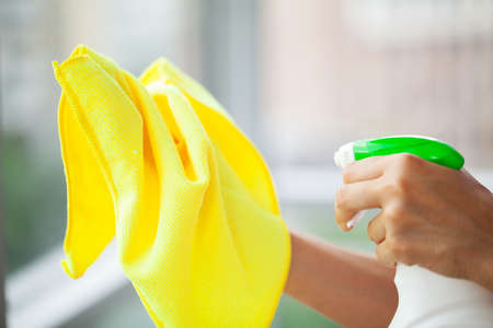 Professional cleaning lady cleans table using a sponge and sprayの写真素材
