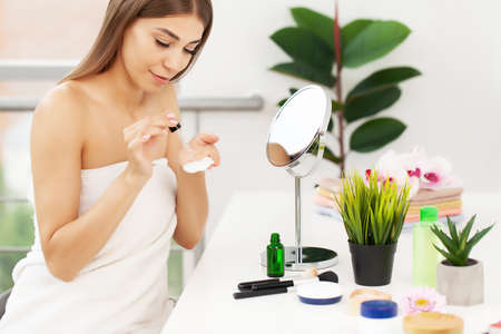 Attractive young woman applying serum on face with pipetteの写真素材