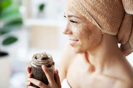 Young woman applying scrub on face in bathroomの写真素材
