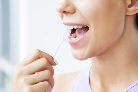 Portrait of beautiful woman cleaning teeth with dental flossの写真素材