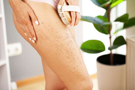 Woman arm holding dry brush to top of her leg, cellulite treatment and dry brushing.の写真素材
