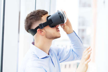 Young man wearing virtual reality glasses in modern office.