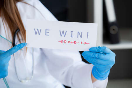 Covid-19, woman doctor holds a form with the text we win.の写真素材
