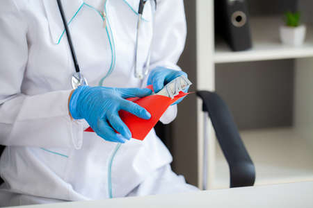 The concept of receiving payment by doctors, red envelope with dollars on the doctor