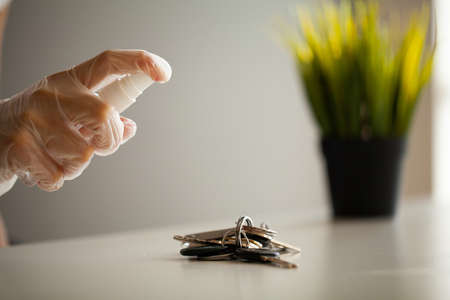 Woman disinfecting keys with disinfectant on the table