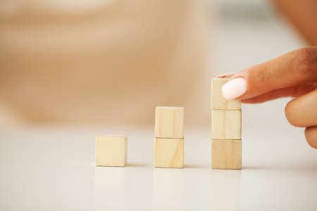 Hand putting and stacking blank wooden cubes on table with copy space for input wording and infographic icon.の写真素材
