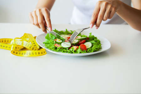 Closeup of fresh salad in a bowl and yellow measure tape