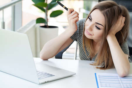 Attractive businesswoman working on laptop in her workplace.
