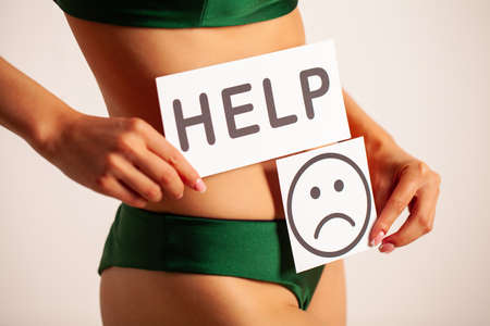Woman Health, Female Body Holding Sad Smile Card Near Stomach.の写真素材