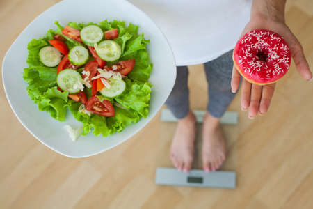Woman makes a choice between harmful and healthy foodsの写真素材