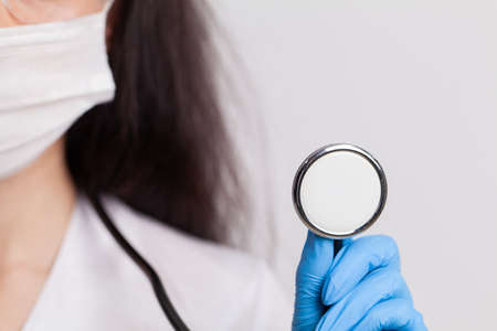 A female doctor in a white coat with a phonendoscope in her hands.の写真素材