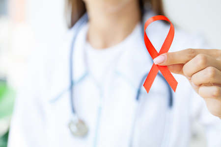 Doctor holding a red ribbon as a symbol of AIDS.