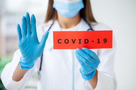 Doctor holding a paper card with text covid-19の写真素材
