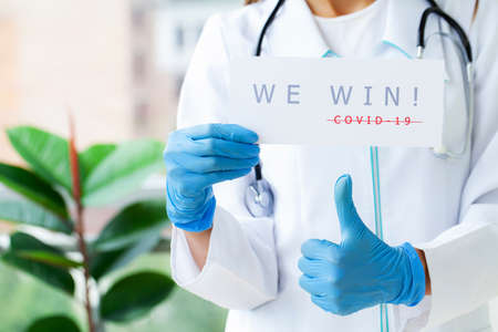 Covid-19, woman doctor holds a form with the text we win.の写真素材