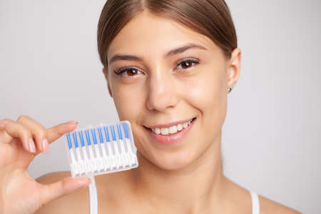 The woman uses brushes to clean the interdental spaces