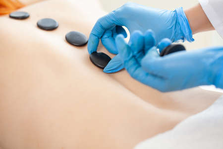 Young woman getting hot stone massage in spa salon.