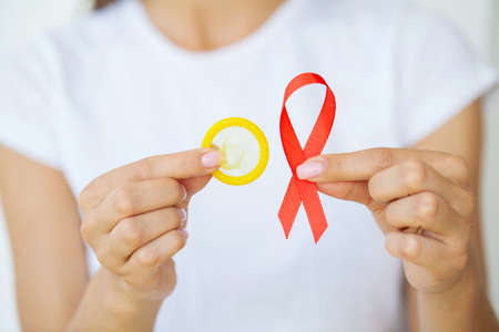 Attractive businesswoman with red ribbon and condom showing in handsの写真素材