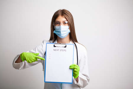 Doctor in a white coat holds a letter with text next stepsの写真素材