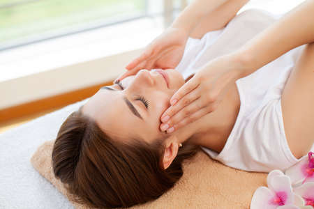 Young pretty woman enjoying face massage procedureの写真素材