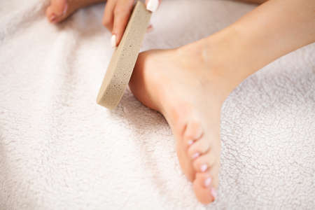Woman cleans the heel of the foot with pumiceの写真素材