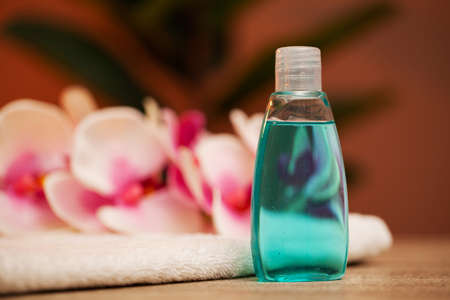 Cosmetic shampoo dispenser bottle with towels and a rosemary on table in bathroomの写真素材
