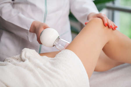 Woman getting anti-cellulite massage of leg with use of vacuum cansの写真素材