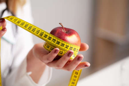 Closeup on measuring apple in caucasian woman hands.の写真素材