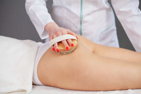 The girl is massaging the skin of the legs with a brushの写真素材