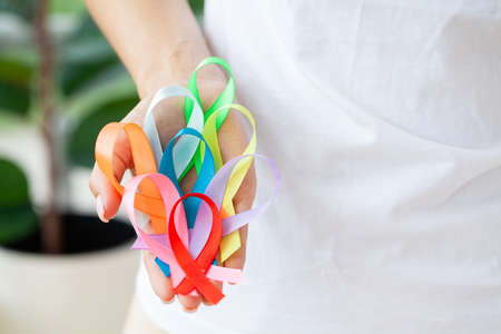 Female doctor holds colored ribbons symbolize awareness of various diseasesの写真素材