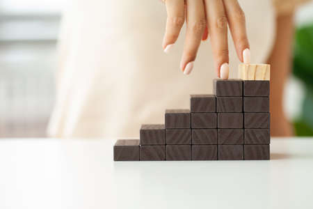 Female fingers climb ladder made of wooden blocksの写真素材