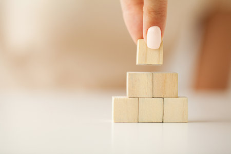Hand picking up one wooden cube on table background.の写真素材