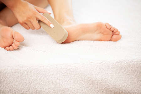 Woman cleans the heel of the foot with pumice at homeの写真素材