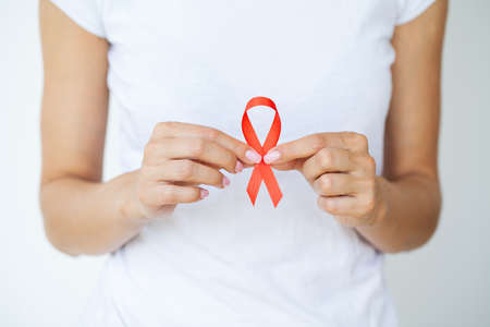 Woman hand holding red ribbon HIV, world AIDS day awareness ribbon.