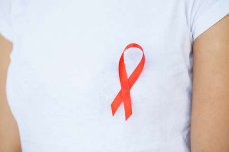 Woman hand holding red ribbon HIV, world AIDS day awareness ribbon.