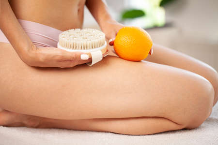 Cellulite problem, young woman holding orange near her legの写真素材