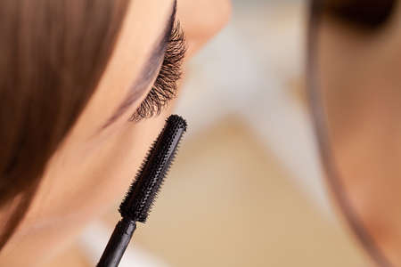 Beautiful young woman doing make up in her bathroom.