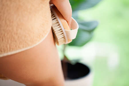 Woman scrubbing her legs with a brush making skin peeling in the bathroomの写真素材