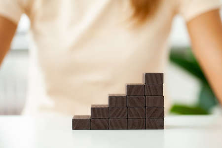 Woman hand stacking wooden blocks in shape of staircase.の写真素材