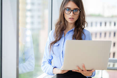 Beautiful business woman is using a laptop and smiling while working in office