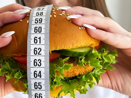 Harmful fatty burger with a measuring tape, concept dietの写真素材
