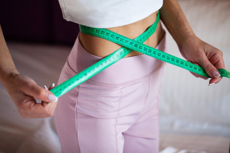 Slim woman measuring her waist with a measure.の写真素材