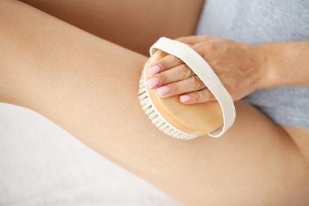 Woman is massaging the skin of the legs with a brush.の写真素材