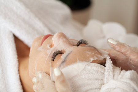 Young woman relaxing with a white textile facial moisturizing mask.の写真素材