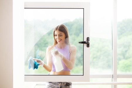 Young woman washing window with sponge in office.の写真素材