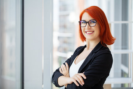 Smiling woman freelancer with red hair working with laptopの写真素材