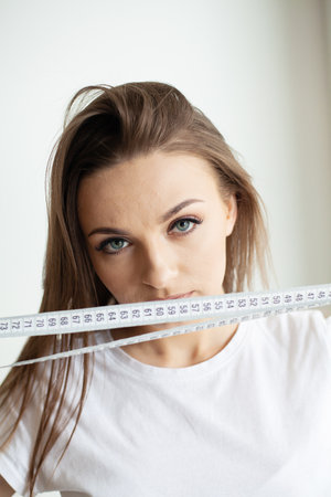 Close up of a young woman holding a measuring tape