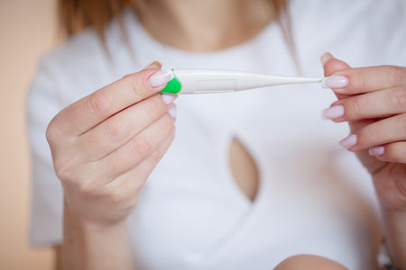 Close up female hands holding a digital thermometerの写真素材