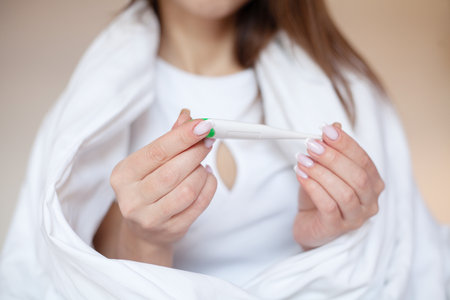 Close up female hands holding a digital thermometerの写真素材