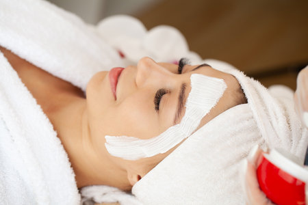 Beautiful woman with mineral mask on her face in spa studioの写真素材