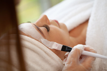 Beautiful woman with mineral mask on her face in spa studioの写真素材
